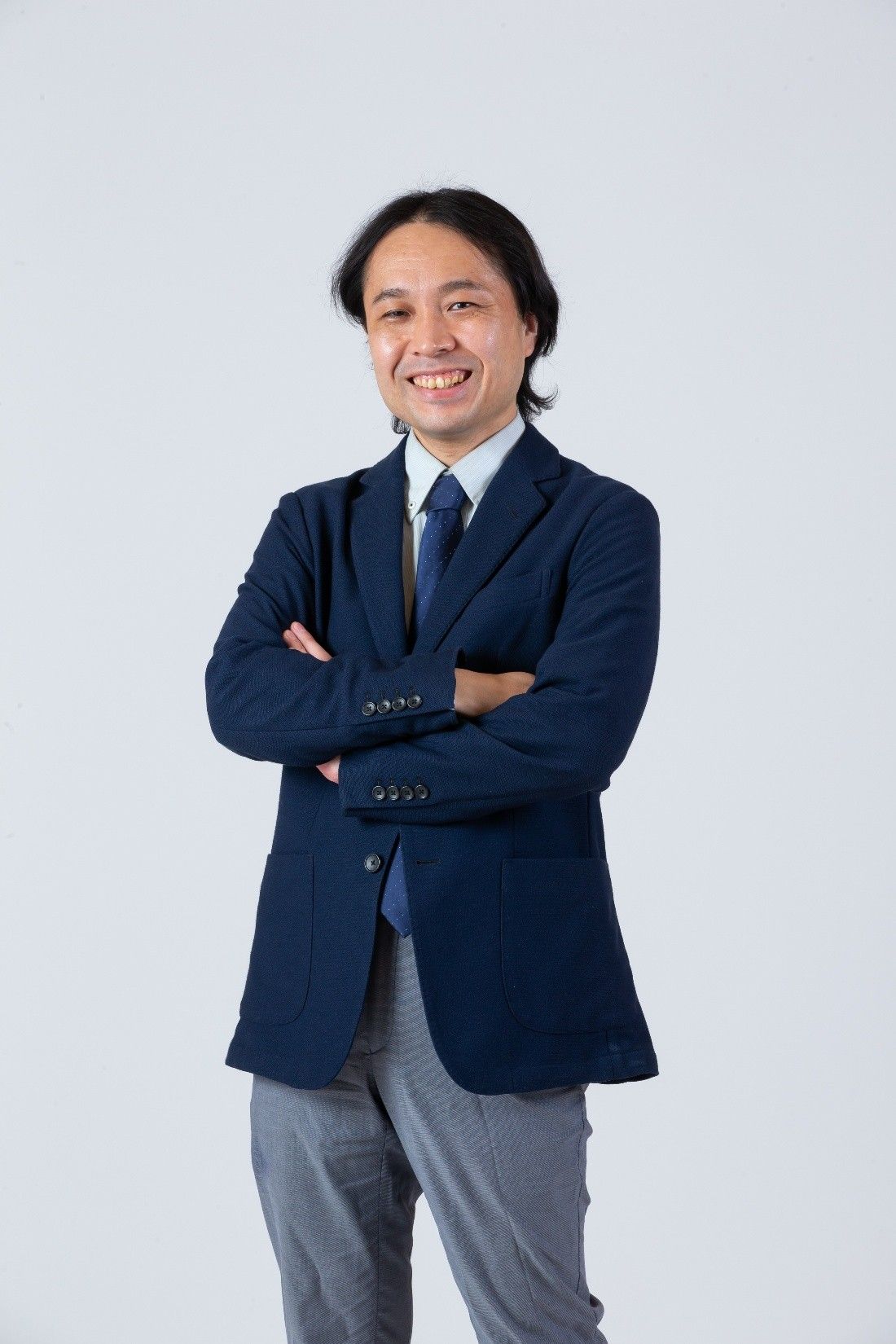 紺色のジャケットを着て腕を組んでいる室山真徳の写真