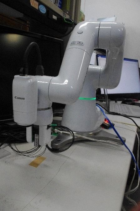 机の横に設置された白いロボットアーム