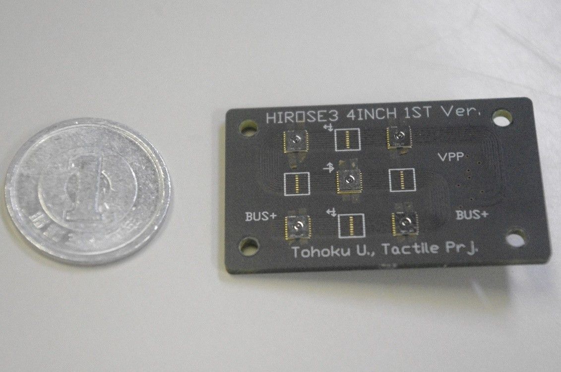「Tohoku U., Tactile Prj.」と印刷された黒い基板に小さなセンサが並んでいる様子と、大きさの比較の1円硬貨